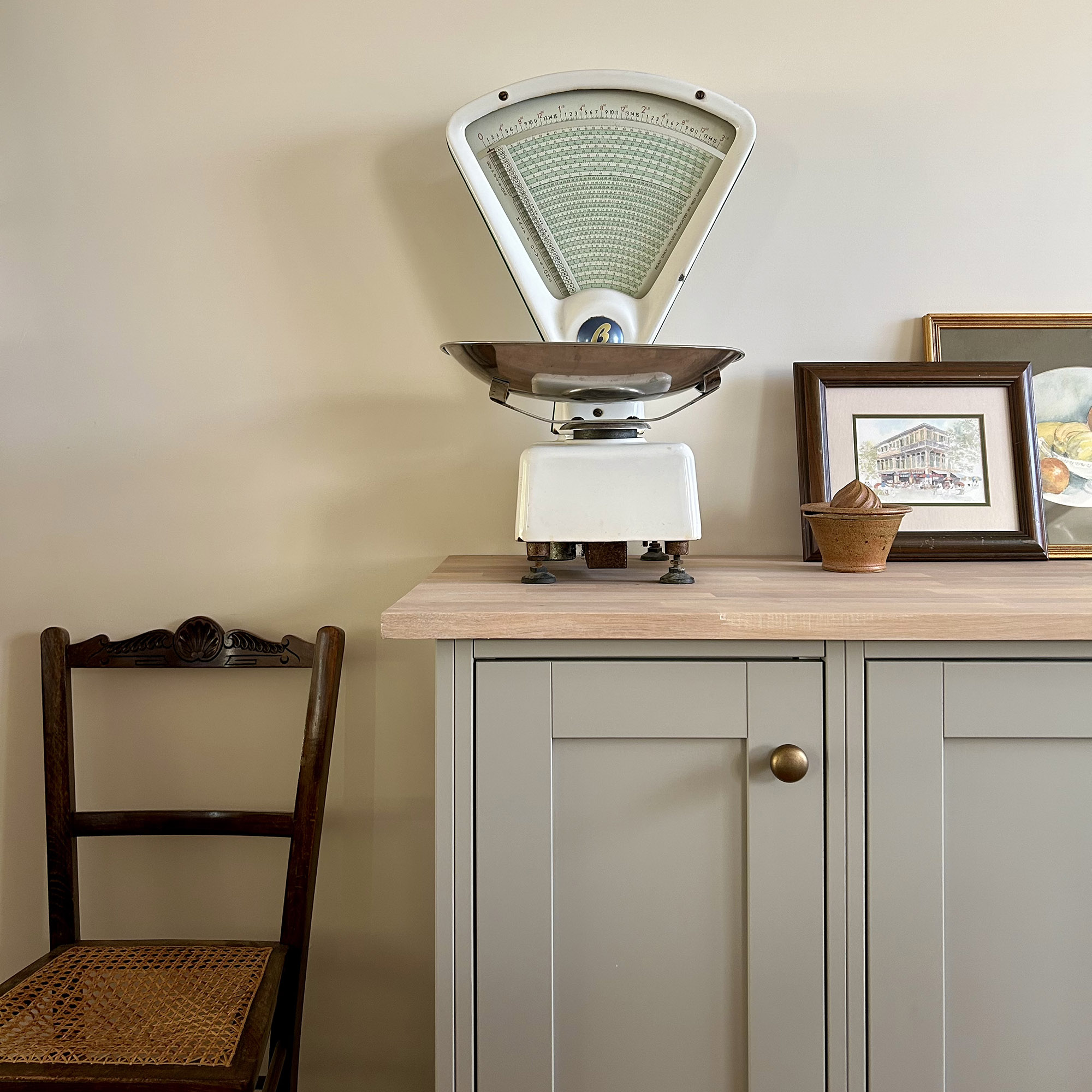 vintage scales on a shaker kitchen cupboard next to a vintage chair