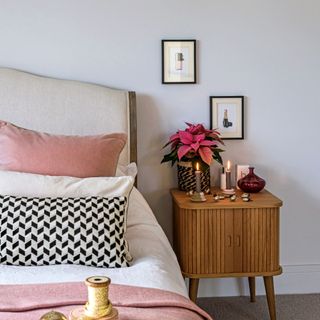 Pink poinsettia plant on wooden bedside table in bedroom