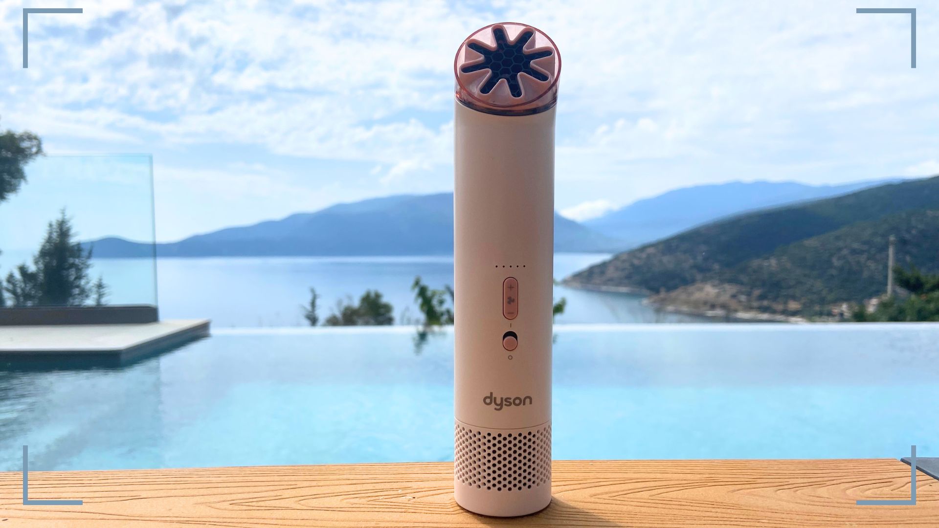 The Dyson HushJet Mini Cool Fan sat on a table in front of a pool with picture corners around it