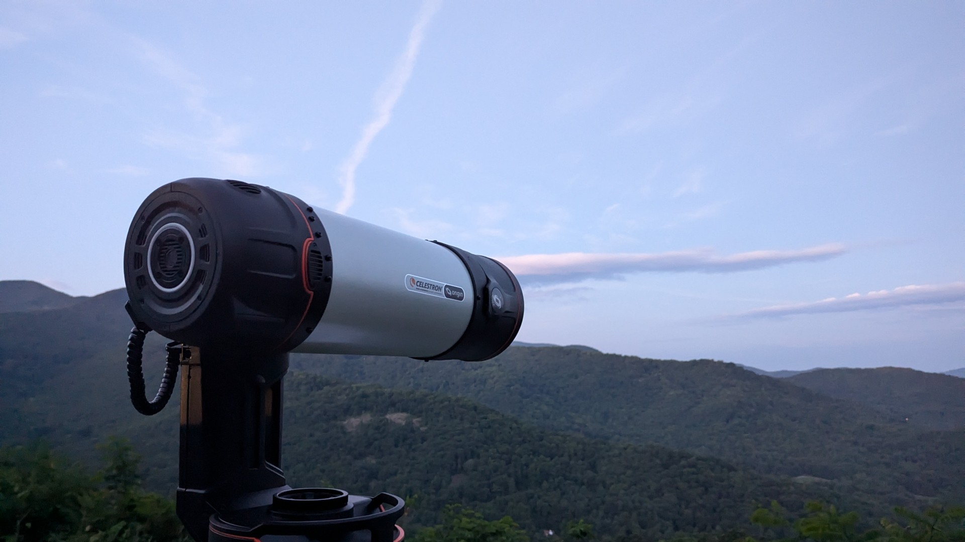 um telescópio preto e branco em um campo com árvores atrás dele