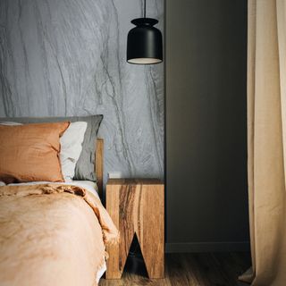 A bedroom with grey marbled walls and a wooden bedside table