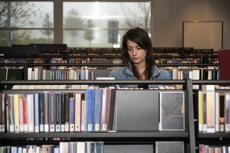 An introverted young woman in the library.