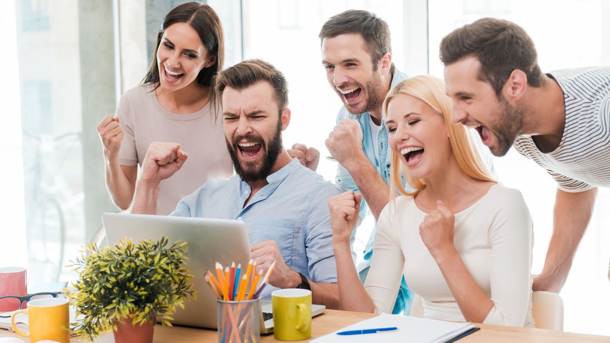 Group of happy business people in smart casual wear looking at the laptop and gesturing