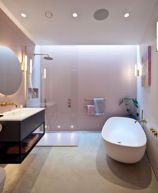 A blush pink decorated bathroom with bath and shower and brass fittings