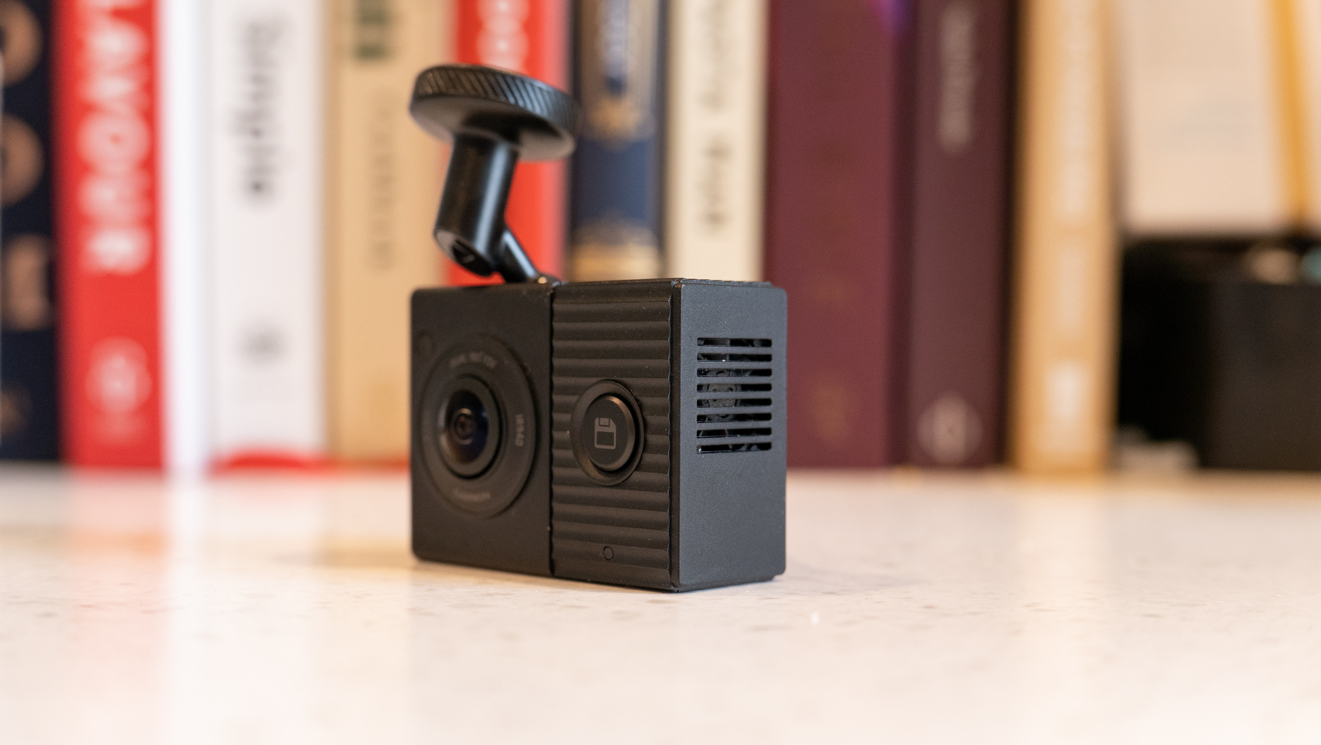 The Garmin Dash Cam Tandem on a table in front of books