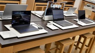 Bild från en elektronikaffär med ett gäng laptops som står uppradade på ett bord.