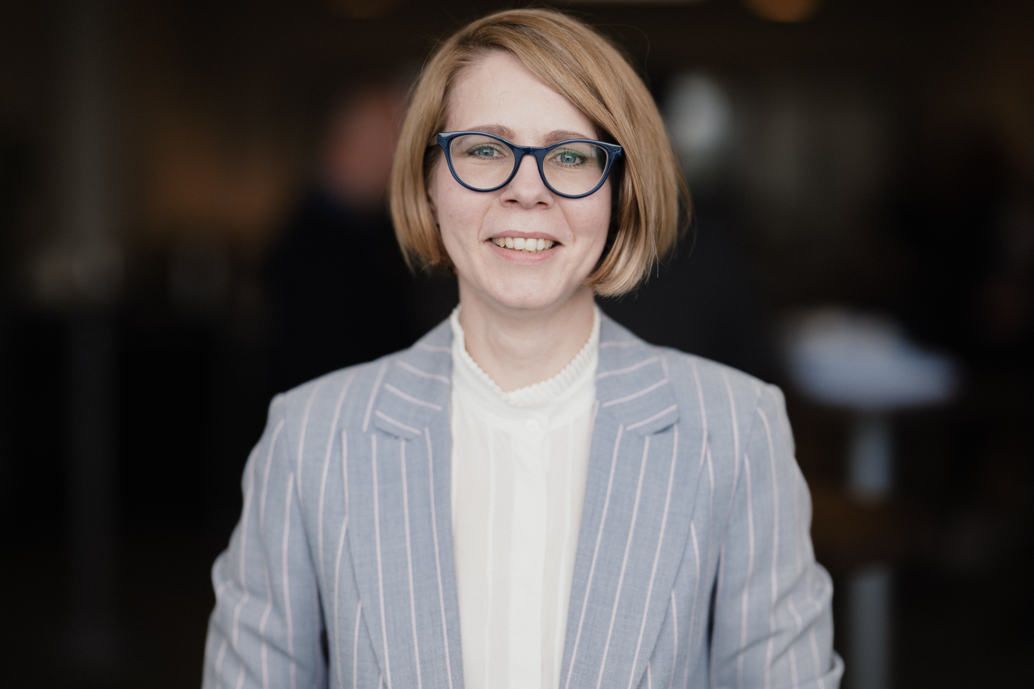A woman with a striped blazer and glasses.