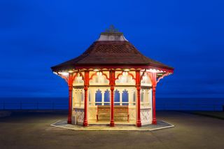 Lit-up Edwardian seafront shelter at dusk, Bexhill-on-Sea, East Sussex, England, United Kingdom