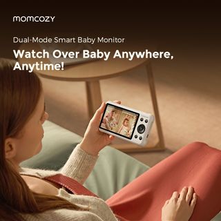 A woman sits on a couch and looks over her baby with the baby monitor screen for the Dual-Mode smart baby monitor with text overlaid that says "Watch over baby anywhere, anytime!"