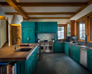 L-shaped kitchen layout in teal with teal island and pattern tiled backsplash