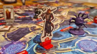 A dragonborn Fighter token on the Horrified: Dungeons & Dragons game board beside a Beholder model