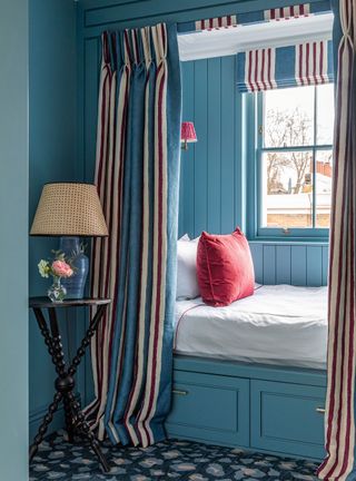 Blue bedroom with cozy corner and striped curtains