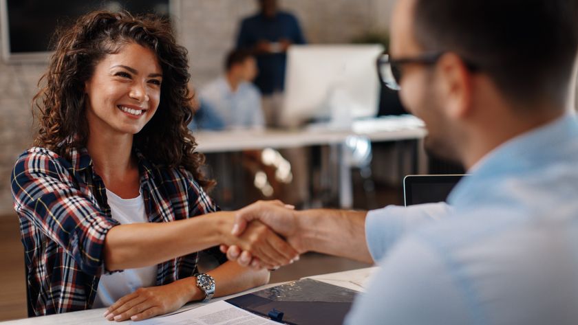 A young woman and a man shaking hands over a job contract