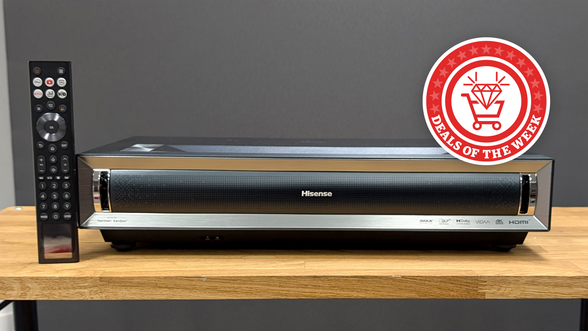 The Hisense PX3 Pro projector laid on a table with the remote, with the deals of the week logo overlaid