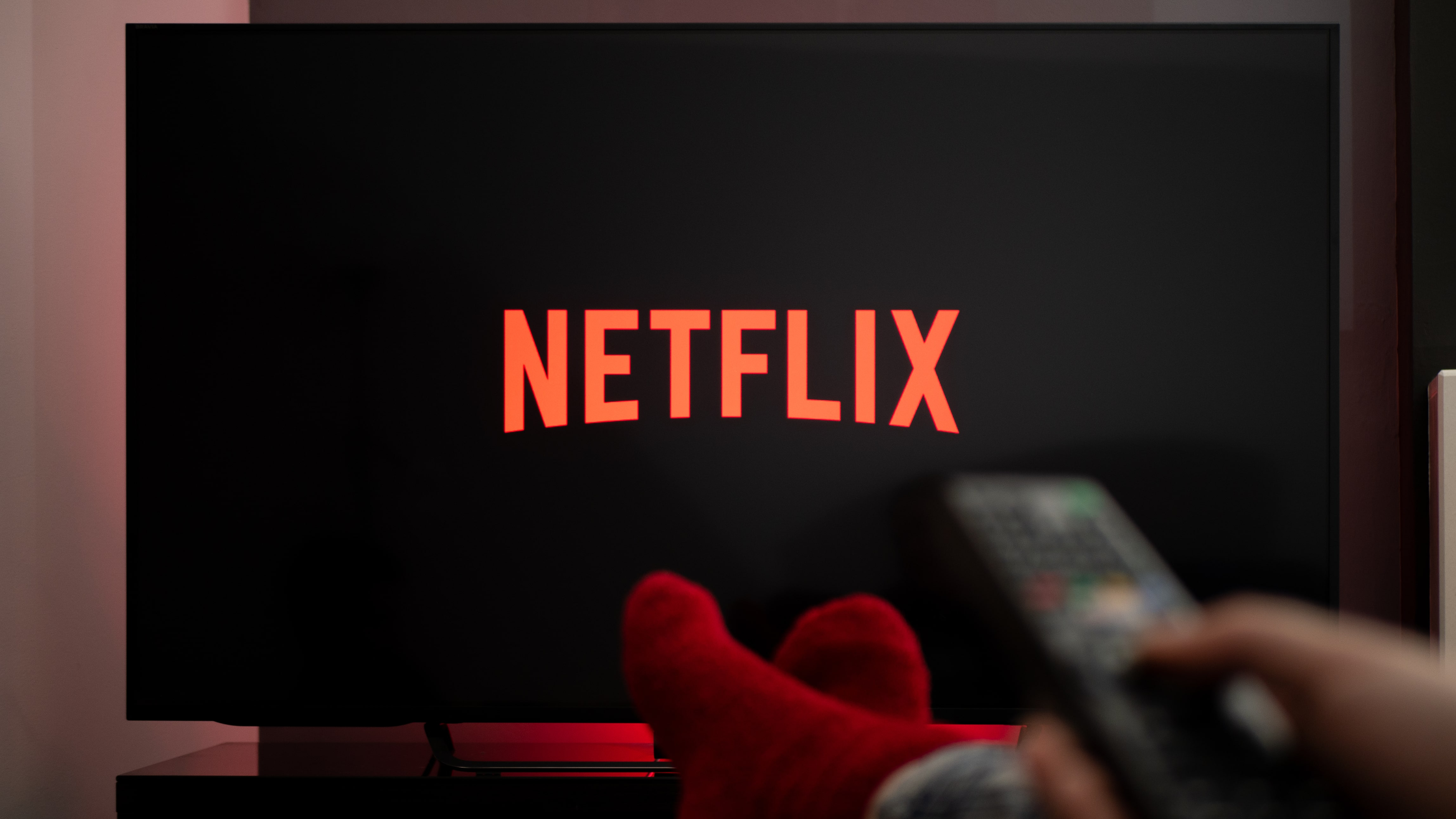 A man watching Netflix on TV with his feet resting on a table in front of him
