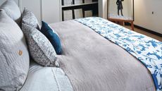 Blue bedroom with duvet cover, throw and pillows styled on bed