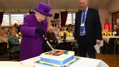 Queen Elizabeth cutting a cake.