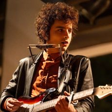 timothee chalamet as bob dylan playing guitar and a harmonic in the movie a complete unknown