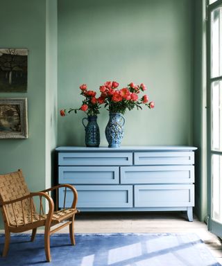 Green painted walls alongside upcycled blue drawers with flowers