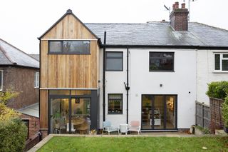 The rear exterior of the house with the new two-storey extension clad in wood