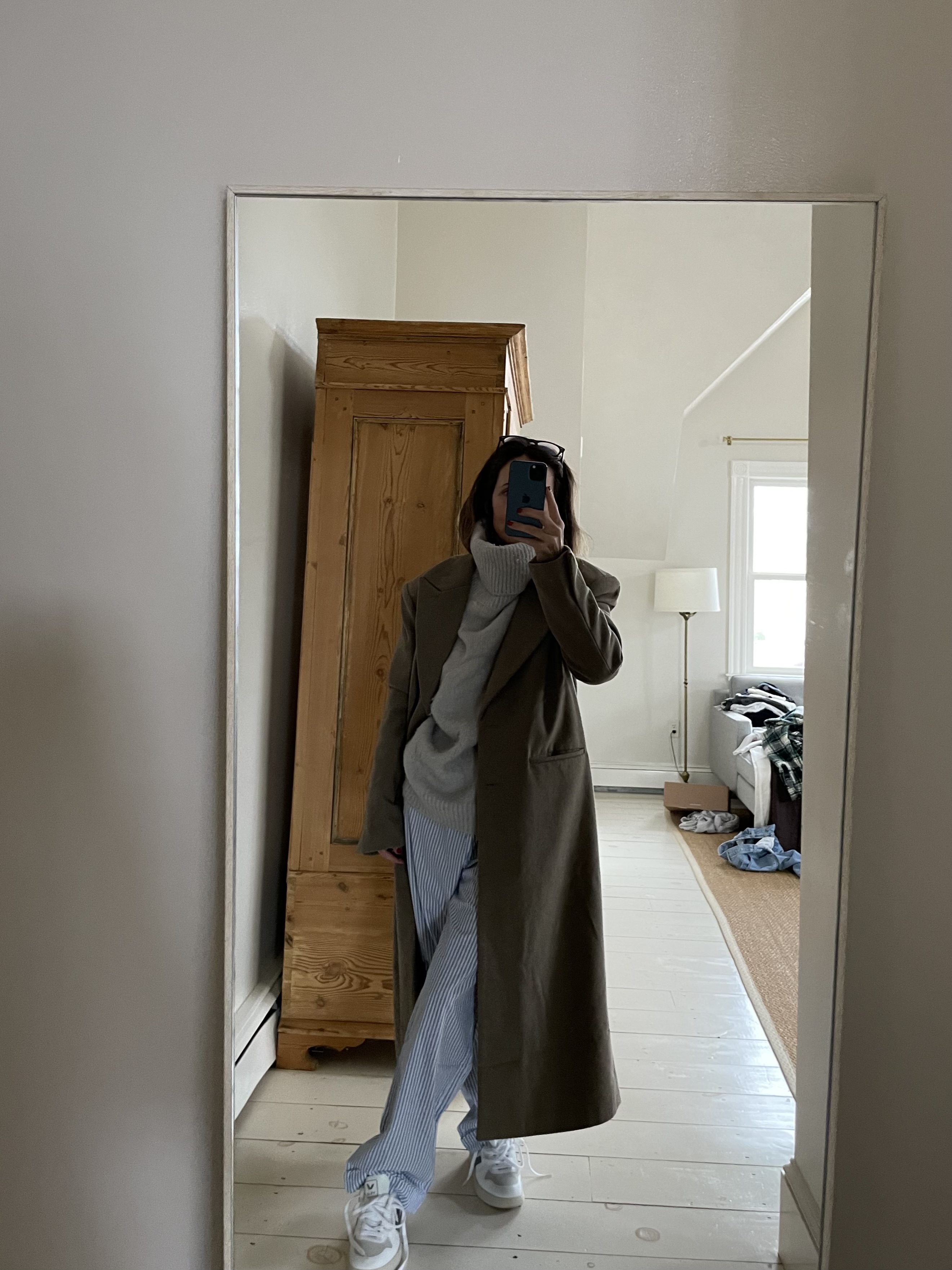 Larissa Mills wearing blue striped pajama pants, a gray turtleneck sweater, and brown wool coat