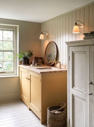 small laundry room with yellow painted cabinet, green wall and wall lights