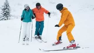 A ski instructor demonstrating the ski plow to two students