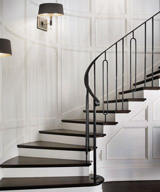 A black and white staircase with Miles Wall light sconce