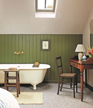 bedroom with white bathtub, green tongue and groove panelling and patterned wallpaper