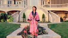 ‘Suburbia. Building the American Dream’ exhibition photo: woman in pink robe in front of grand suburban house