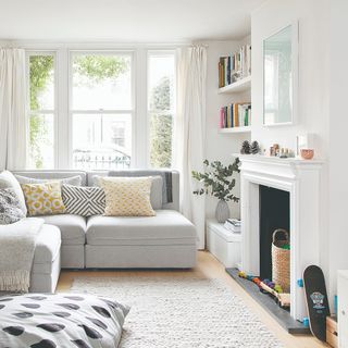 A bright living room with a non-working fireplace used for toy storage and a rug in front of it