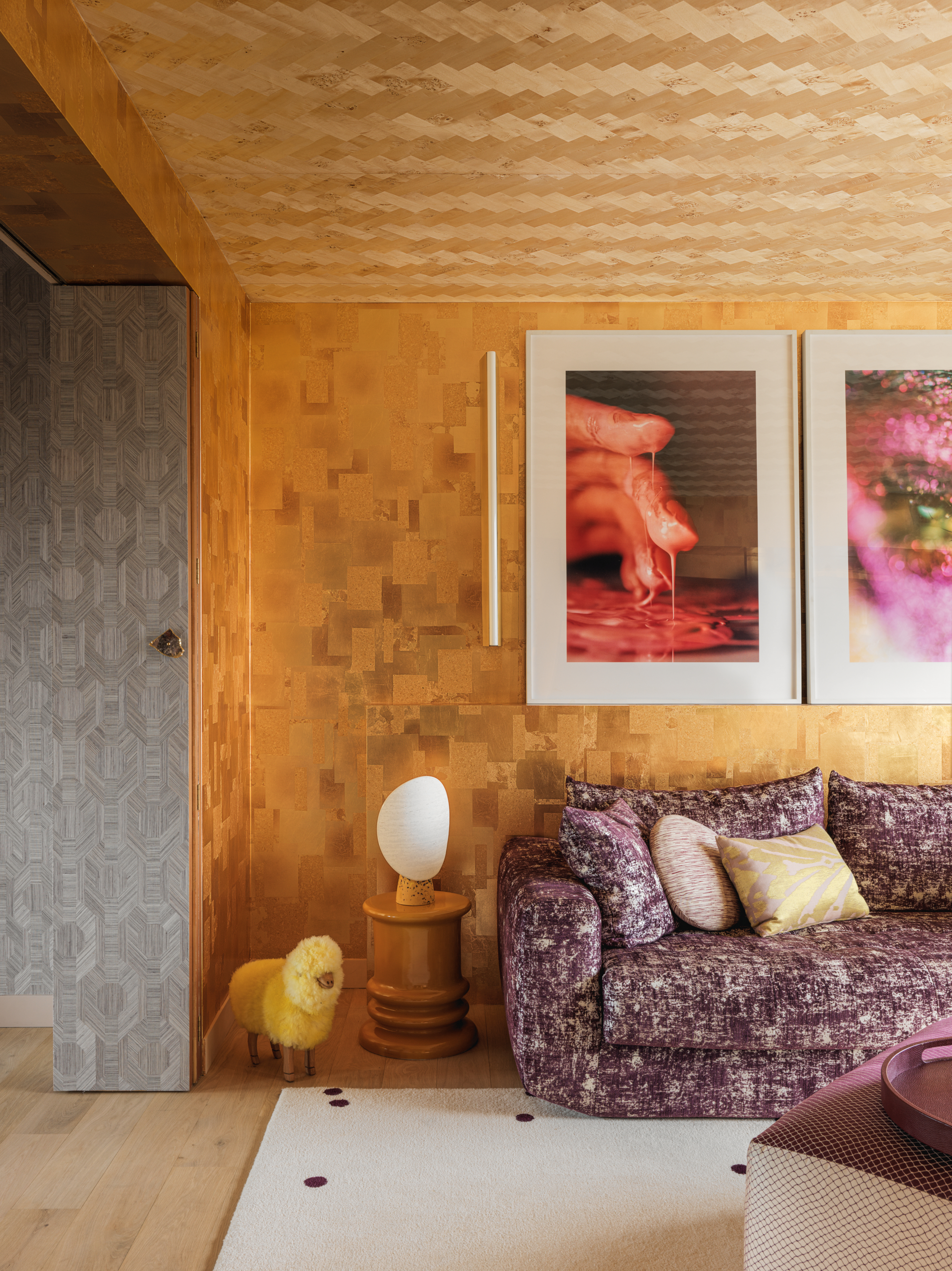 TV room with walls in golf leaf, ceiling in chevron wood wallpaper, purple sofa and wood side table