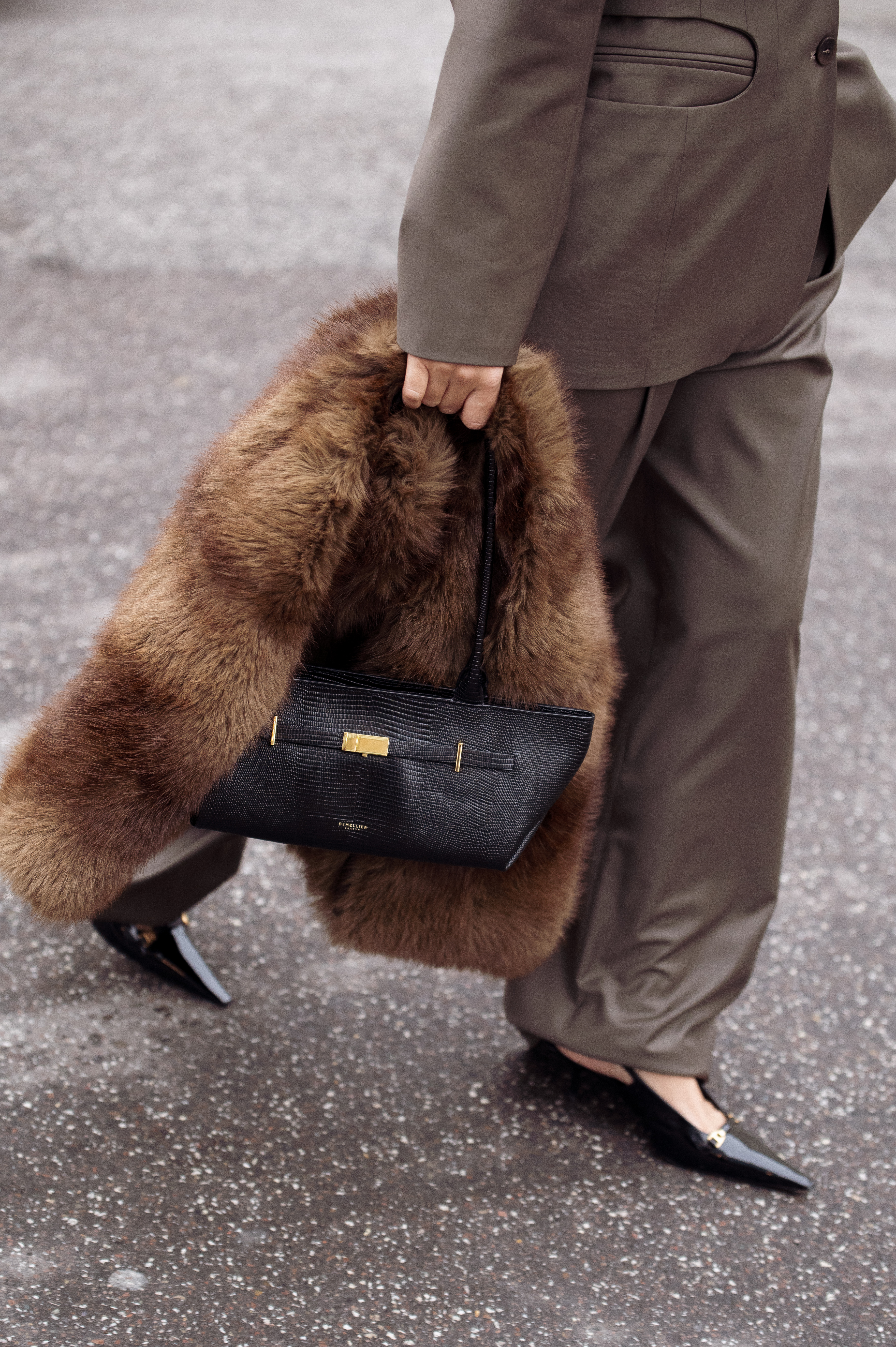 COPENHAGEN, DENMARK - DECEMBER 06: Gili Biegun wears structured olive brown suit, holding a fur scarf, Demellier London The New York Shoulder east west bag in black lizard and Saint Laurent slingback kitten heels on December 06, 2025 in Copenhagen, Denmark. (Photo by Raimonda Kulikauskiene/Getty Images)