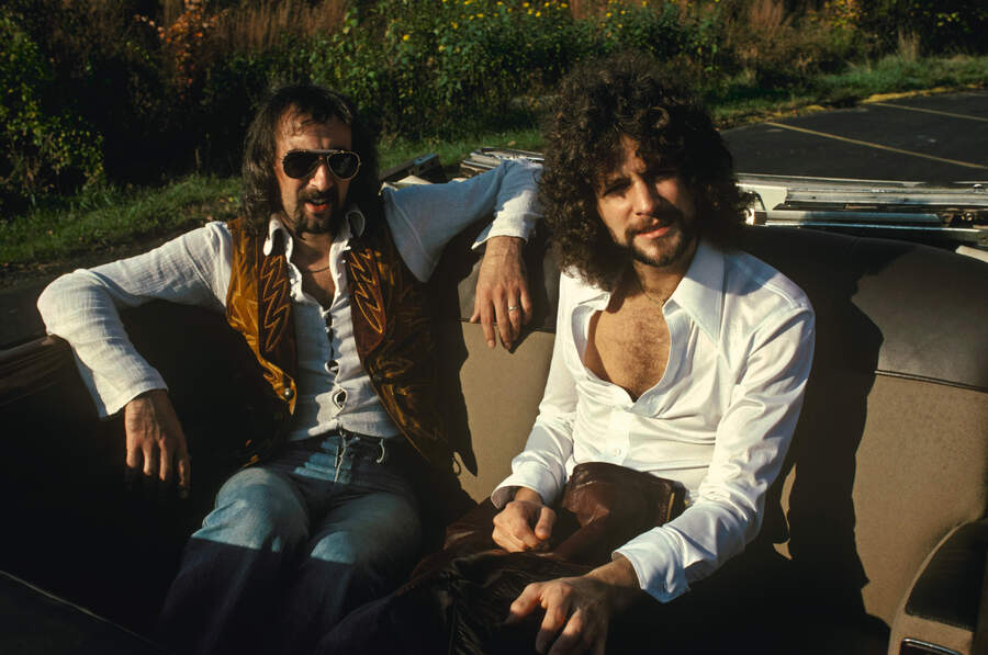 John McVie and Lindsey Buckingham sitting in the back of a convertable car