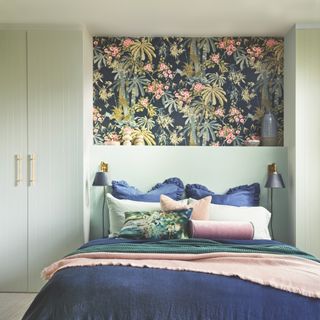 Bedroom with panel of wallpaper above bed and blue wall lights