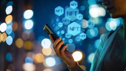 The acronym NFT floats around in balloons above a smartphone held by a woman.