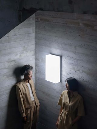 Two women stand in concrete corridor in archive Akris looking at light
