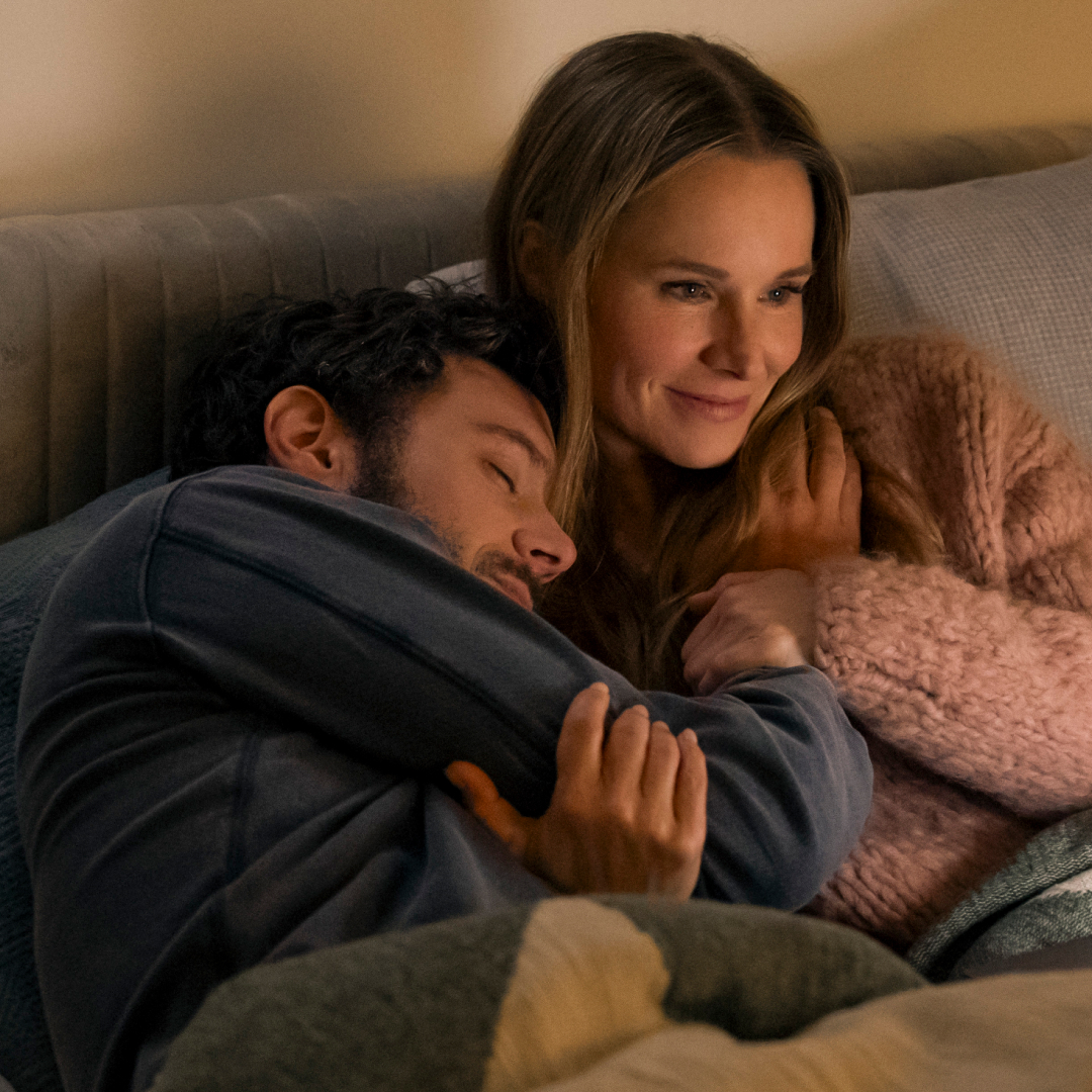 adam brody and kristen bell cuddle while watching a show on a laptop in nobody wants this season 2