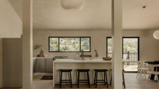 A Japanese-inspired minimalist kitchen and open dining space with paper lanterns, a white island, and black stools
