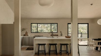 A Japanese-inspired minimalist kitchen and open dining space with paper lanterns, a white island, and black stools