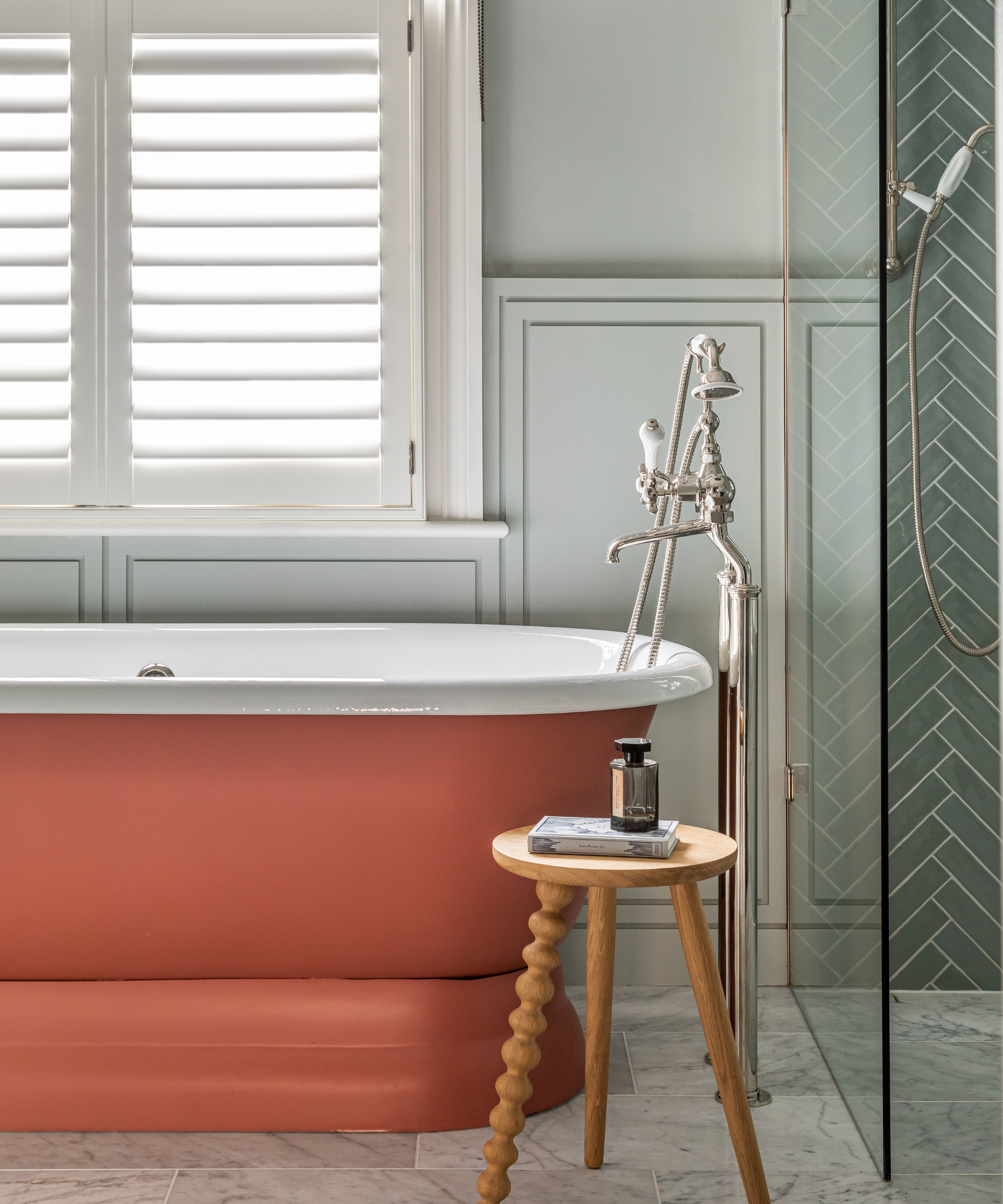 A blue bathroom with an orange roll top bathtub