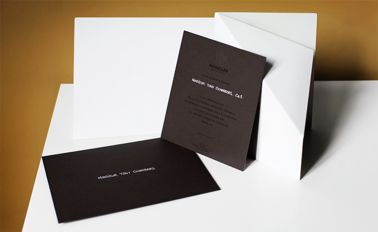 An envelope and card the colour of hearth-warming peat featured de-bossed Moncler branding and foil-printed text