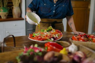 chef pouring dressing on salad