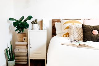 All white bedroom with houseplants and boho style cushions
