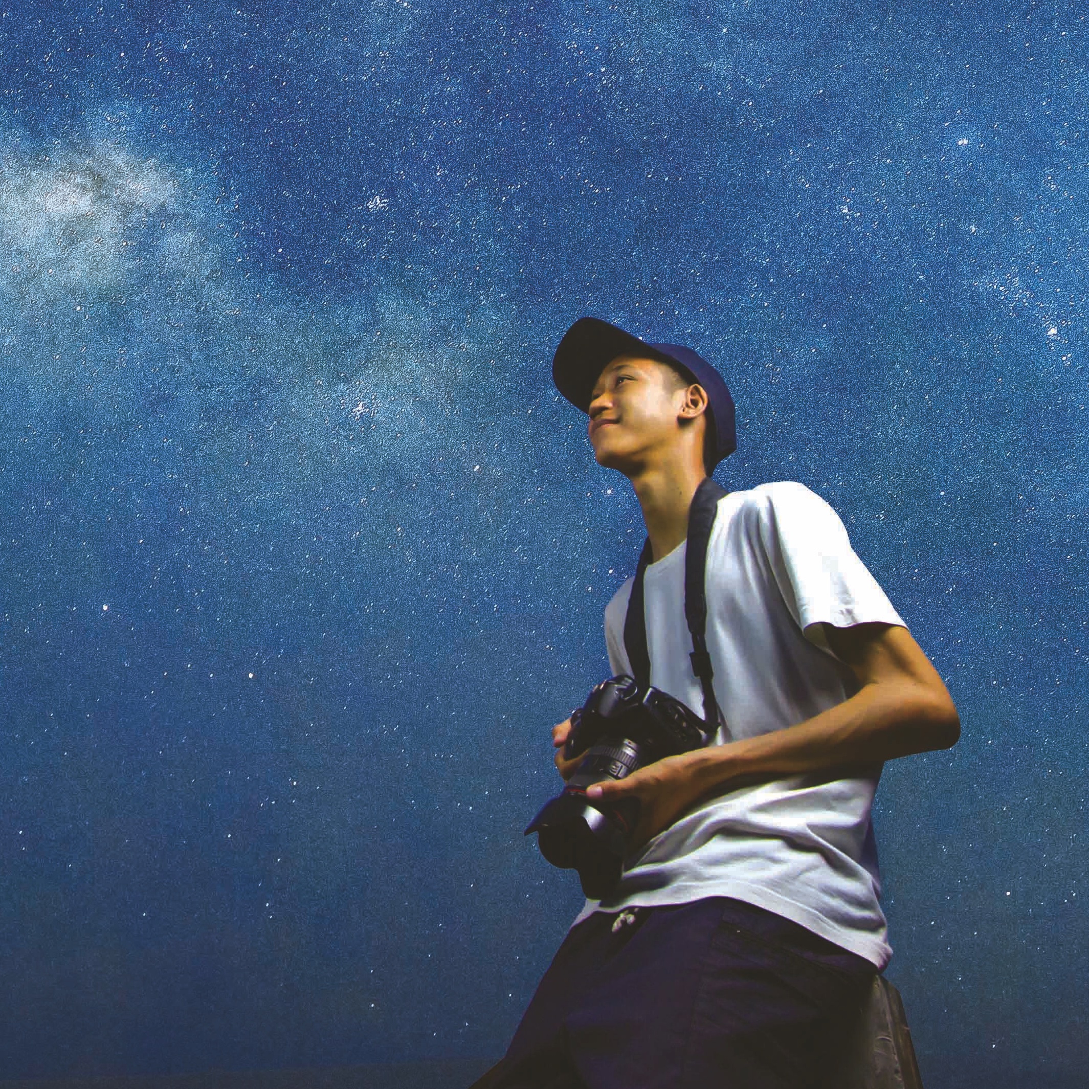 Teenager looking up at the Milky Way while holding a camera