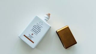 An opened Drunk Elephant D-Bronzi Drops on a white background for w&h's Drunk Elephant Bronzing Drops review.