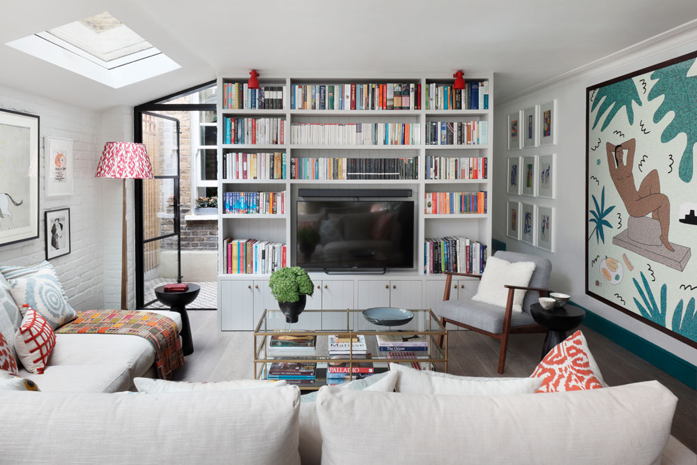 Small modern living room with built in bookcase and rug hanging on the wall