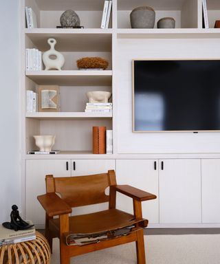 A white living room with built-in bookshelves and a leather armchair