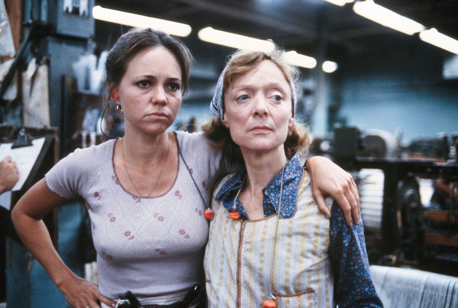 Sally Field puts her arm around another woman in a factory in a still from 'Norma Rae'
