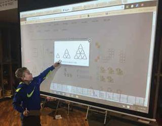 A first-grade student in Springfield Public Schools solves a problem on the board.